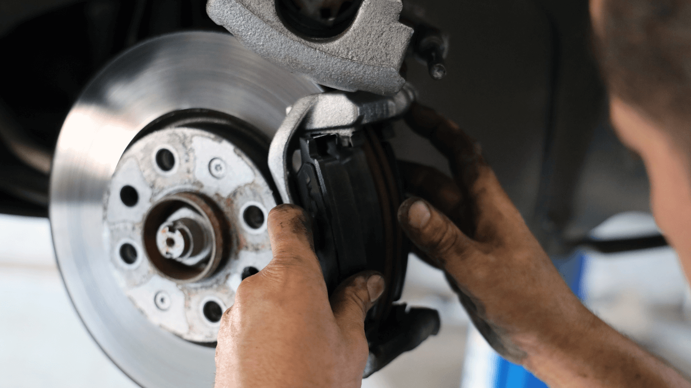 professional auto repair technitian performing a brake and rotor repair job.